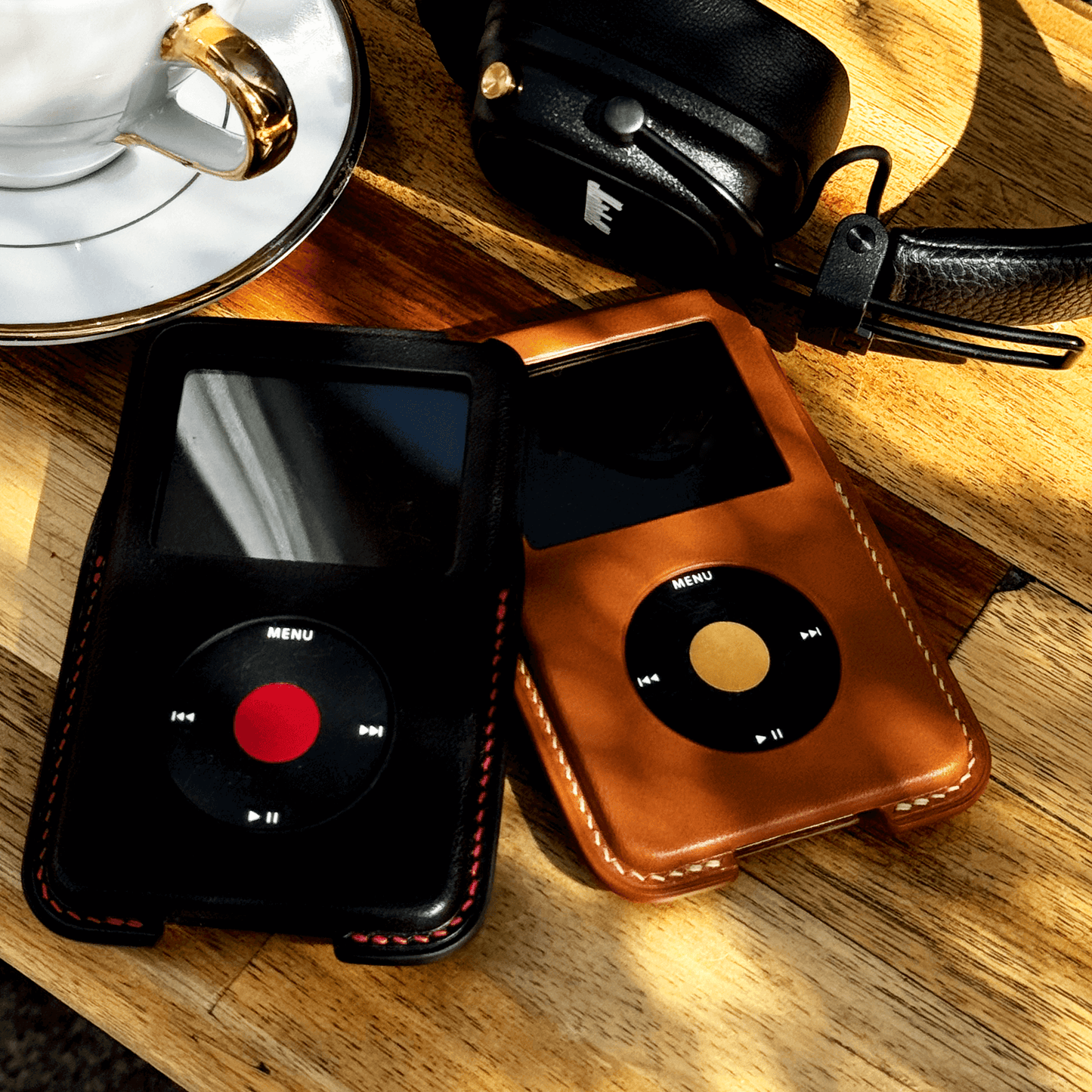 iPod Classic Italian leather case in black and brown on wooden table beside a cup of coffee.